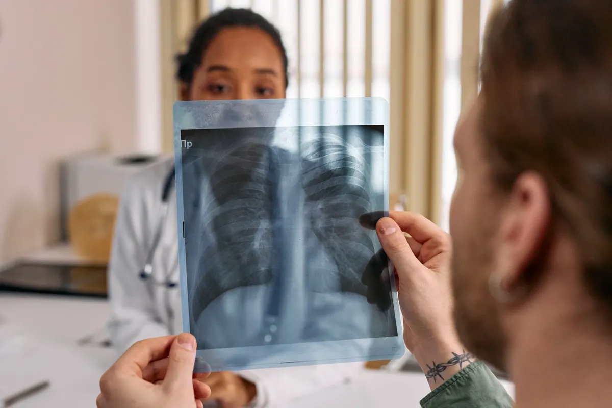 A clinician and patient looking together at a chest X-ray film.